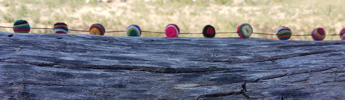Log with colored felt balls on a string